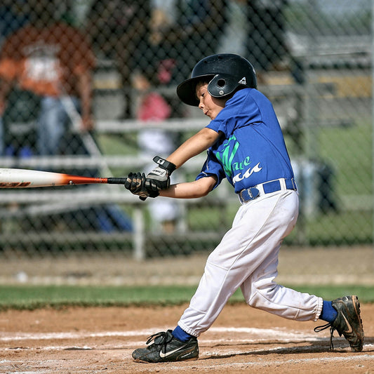 A young baseball player swinging during a game.