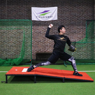 The pitcher at the top of their backswing, preparing to throw.